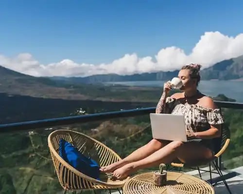carefree-swedish-woman-sitting-on-hotel-balcony-with-laptop-computer