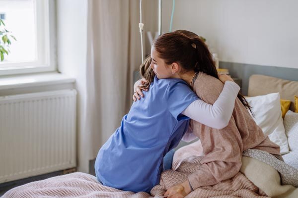 young-doctor-hugging-teenage-girl-in-hospital-room