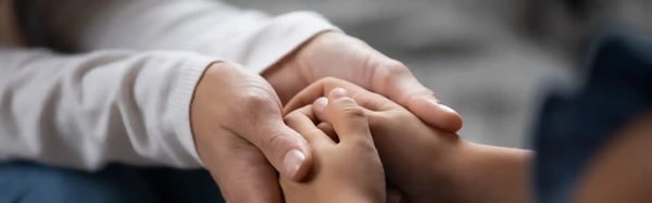 close-up-compassionate-young-foster-parent-holding-hands-of-little