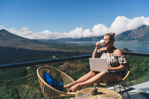 carefree-swedish-woman-sitting-on-hotel-balcony-with-laptop-computer