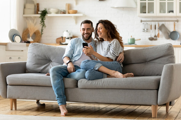 happy-young-woman-and-man-hugging--using-smartphone-together--sitting