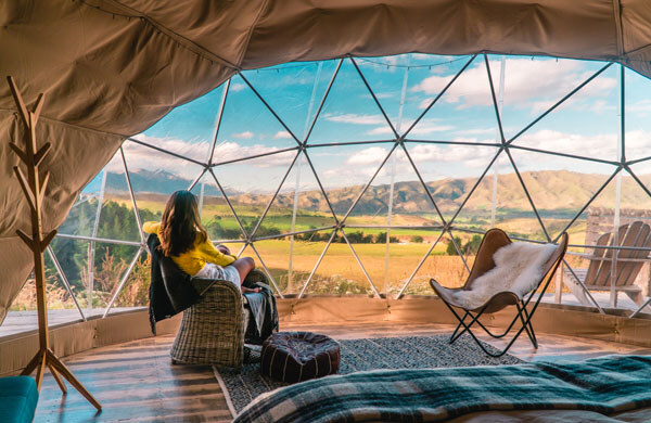 woman-looking-out-at-nature-from-geo-dome-tents-green