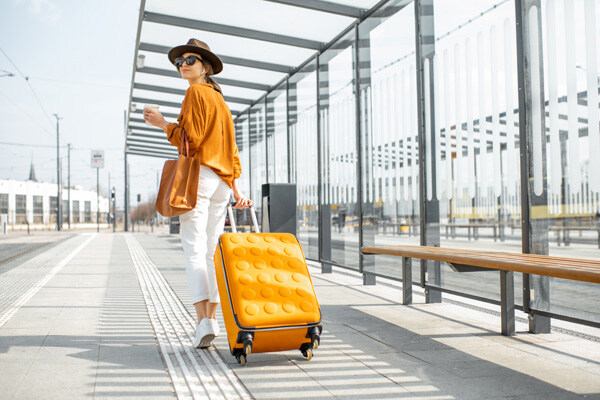 young-female-traveler-walking-with-a-yellow-suitcase-at-the