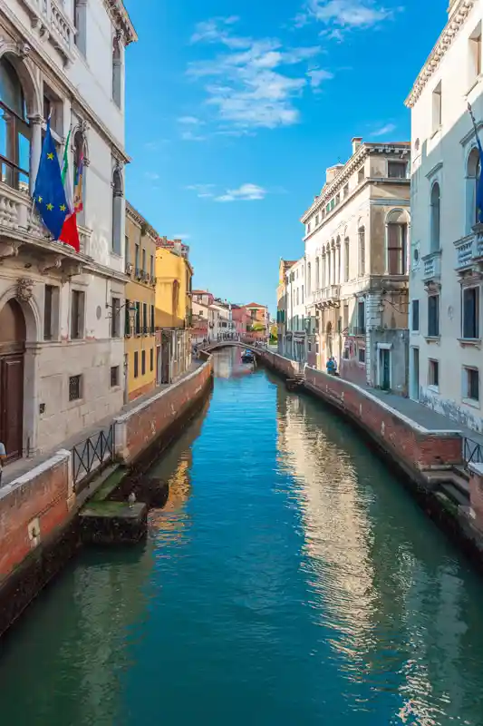 view-of-narrow-canal-with-boats-and-gondolas-in-venice-